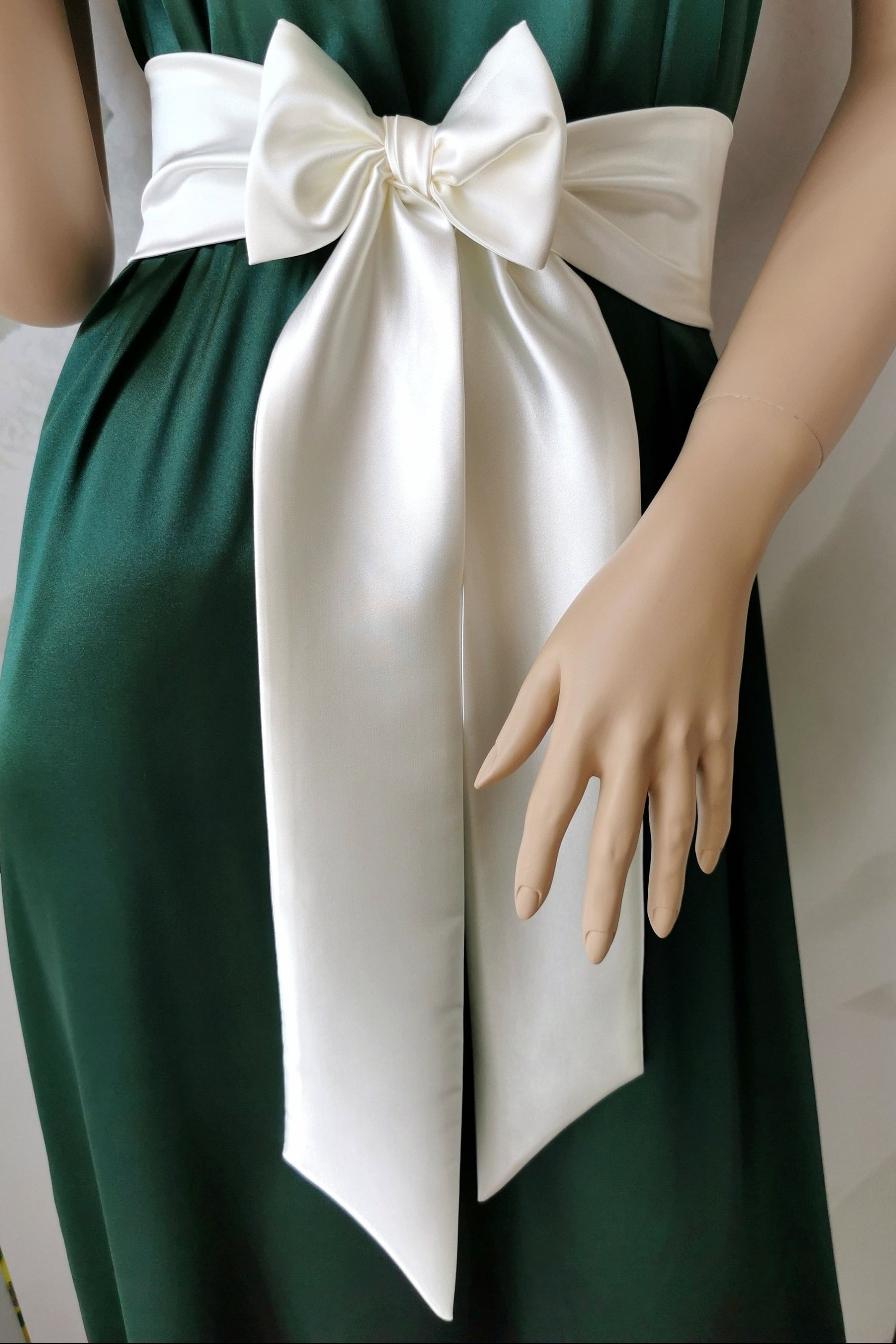 Green dress with a large white bow on a mannequin against a white background