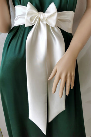 Green dress with a large white bow on a mannequin against a white background