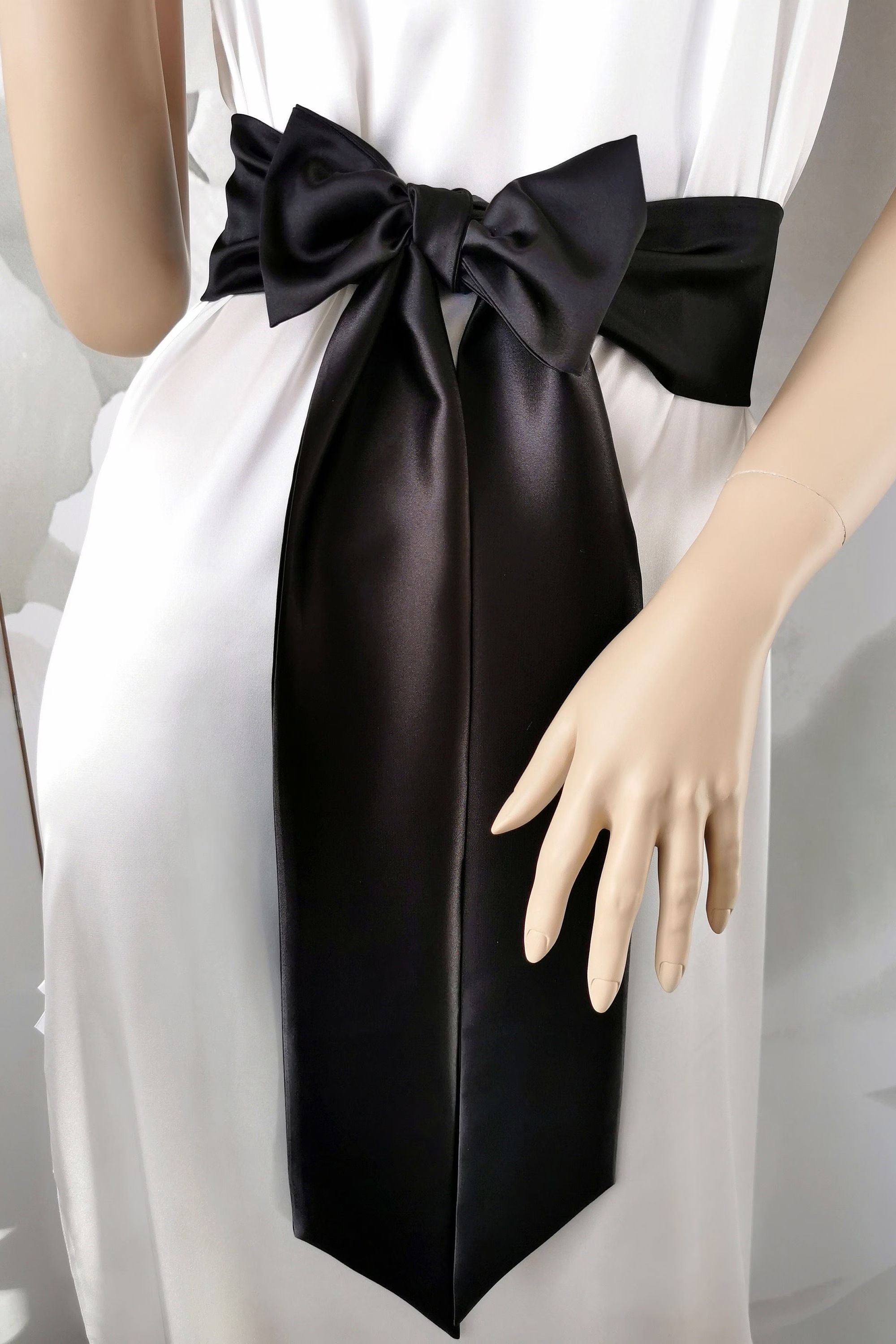 Black satin sash belt tied in a long elegant bow around the waist