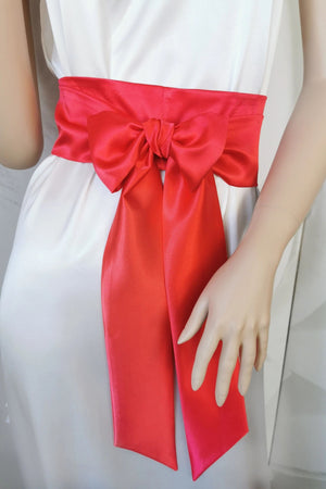 Red satin sash belt tied in a decorative bow on a dress