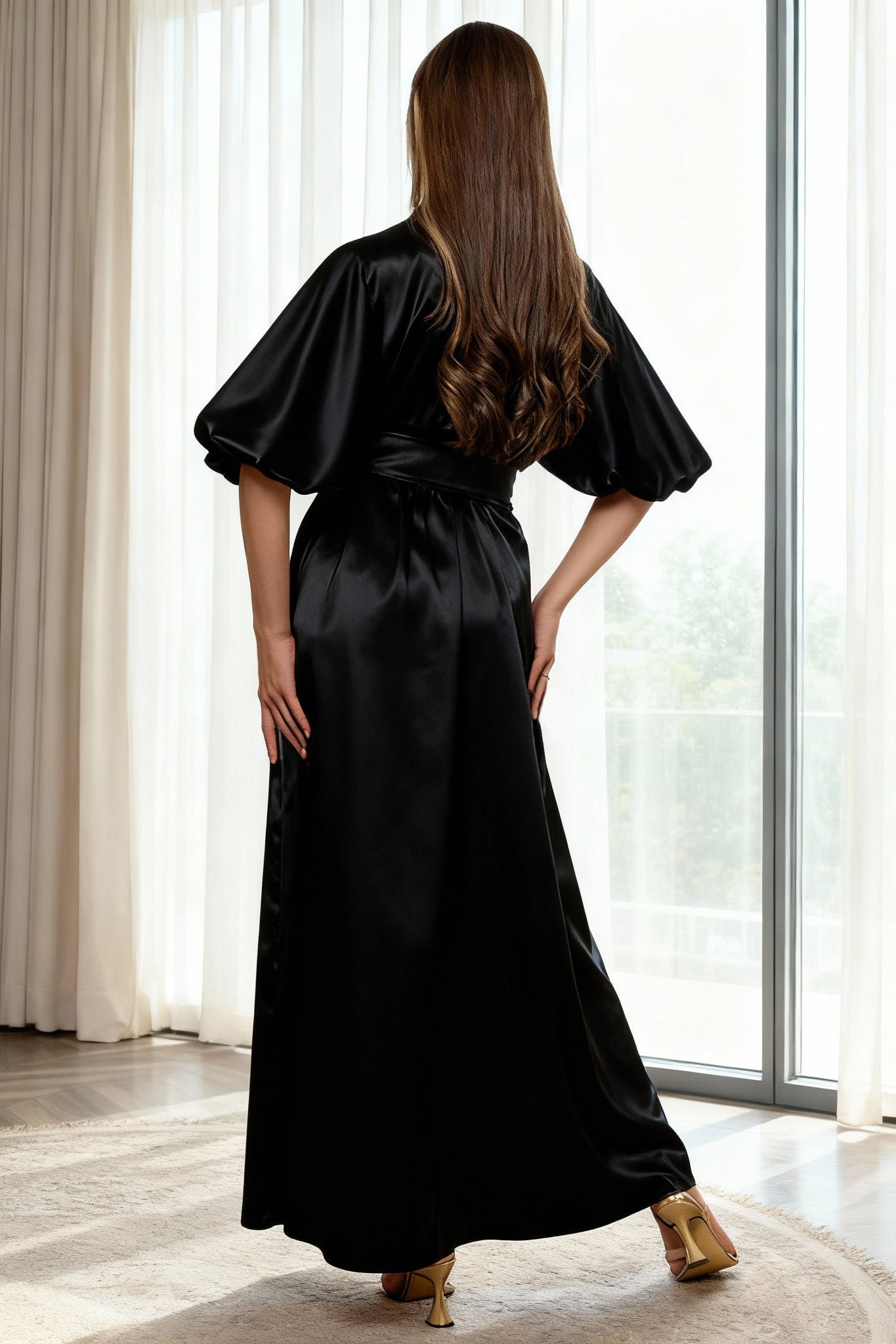 Woman wearing a black satin robe in a bright room with large windows