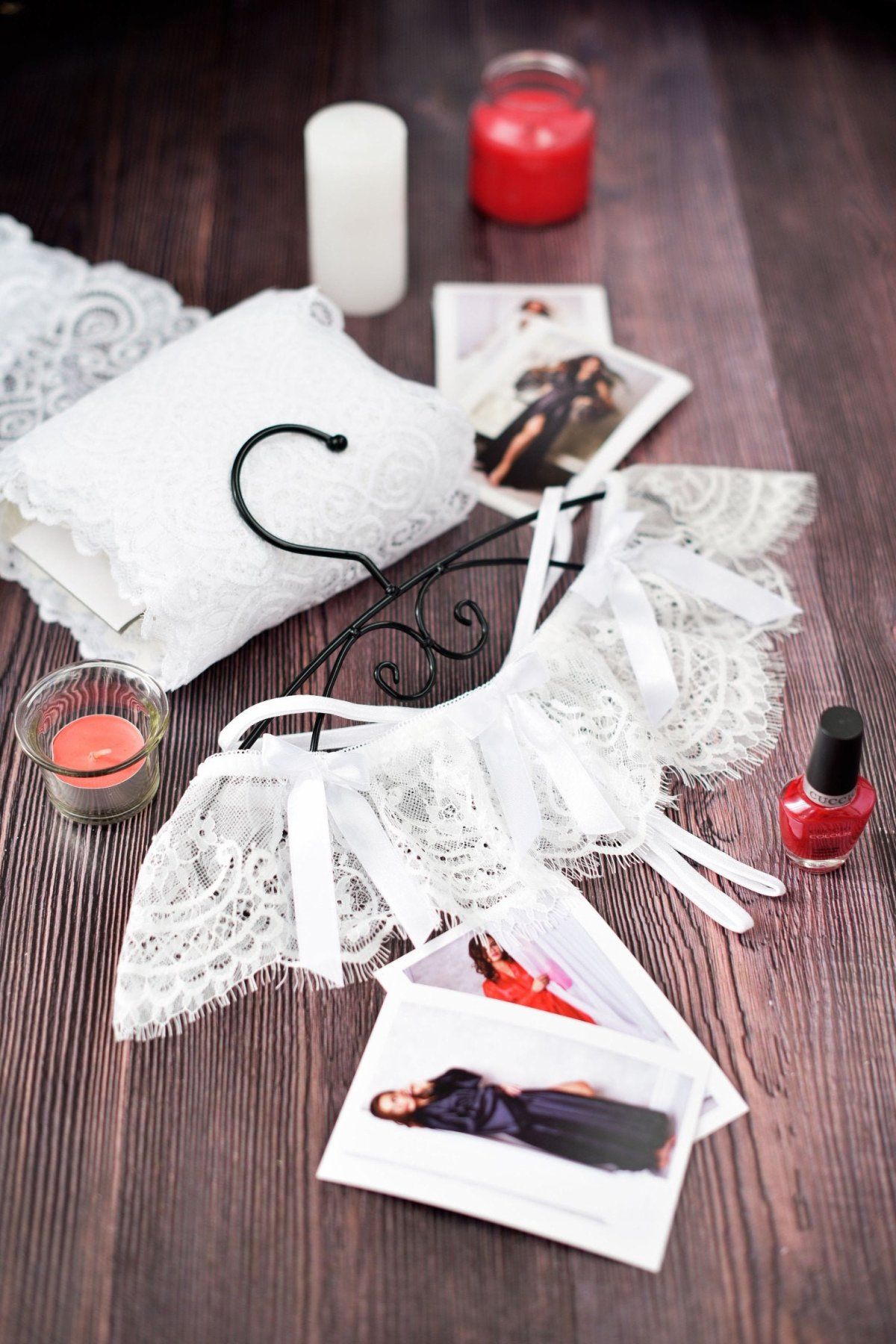 A red lace crotchless thong panty displayed on a hanger, with a matching red cushion and a feather duster in the background.
