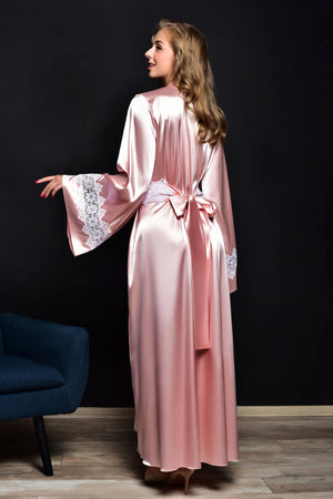 Woman wearing a pink satin robe with lace trim against a black background