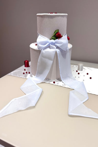White cake with a large bow on a table against a gray background
