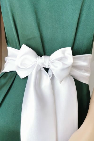 Green dress with a large white bow on a plain background