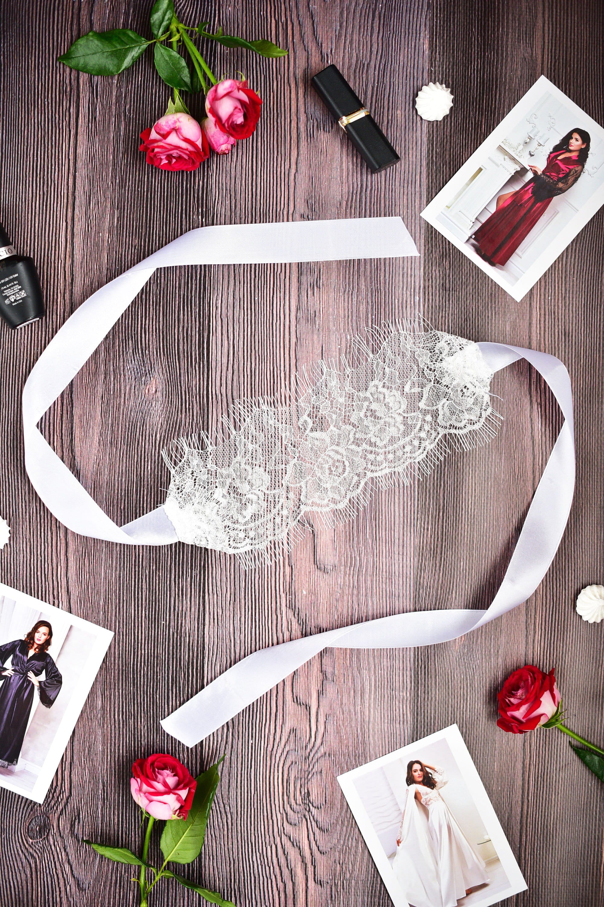 Lace headband on a wooden surface with flowers and fashion magazines.