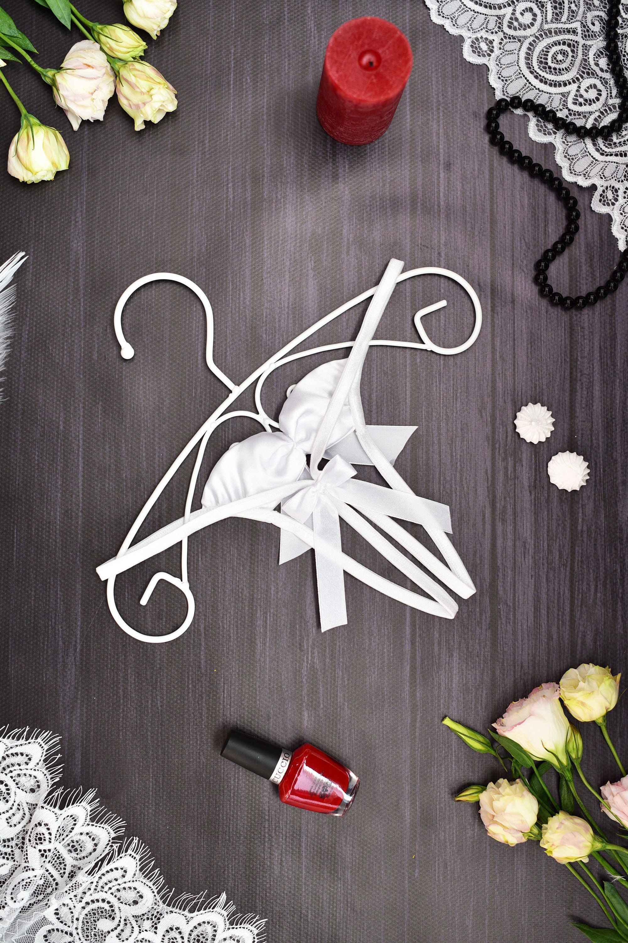 Decorative white hanger with bow on a dark surface with flowers and a candle.