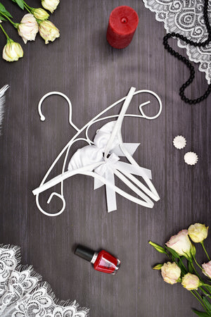 Decorative white hanger with bow on a dark surface with flowers and a candle.